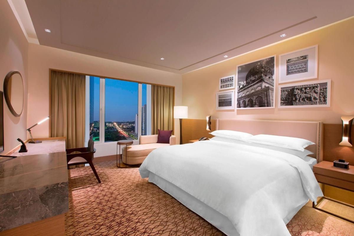 a bedroom with a large white bed and a large window at Sheraton Hyderabad Hotel in Hyderabad