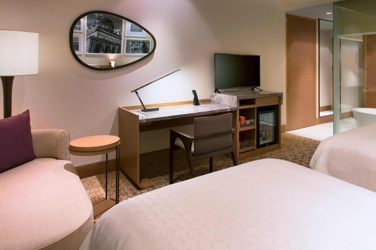 a hotel room with a desk with a television at Sheraton Hyderabad Hotel in Hyderabad