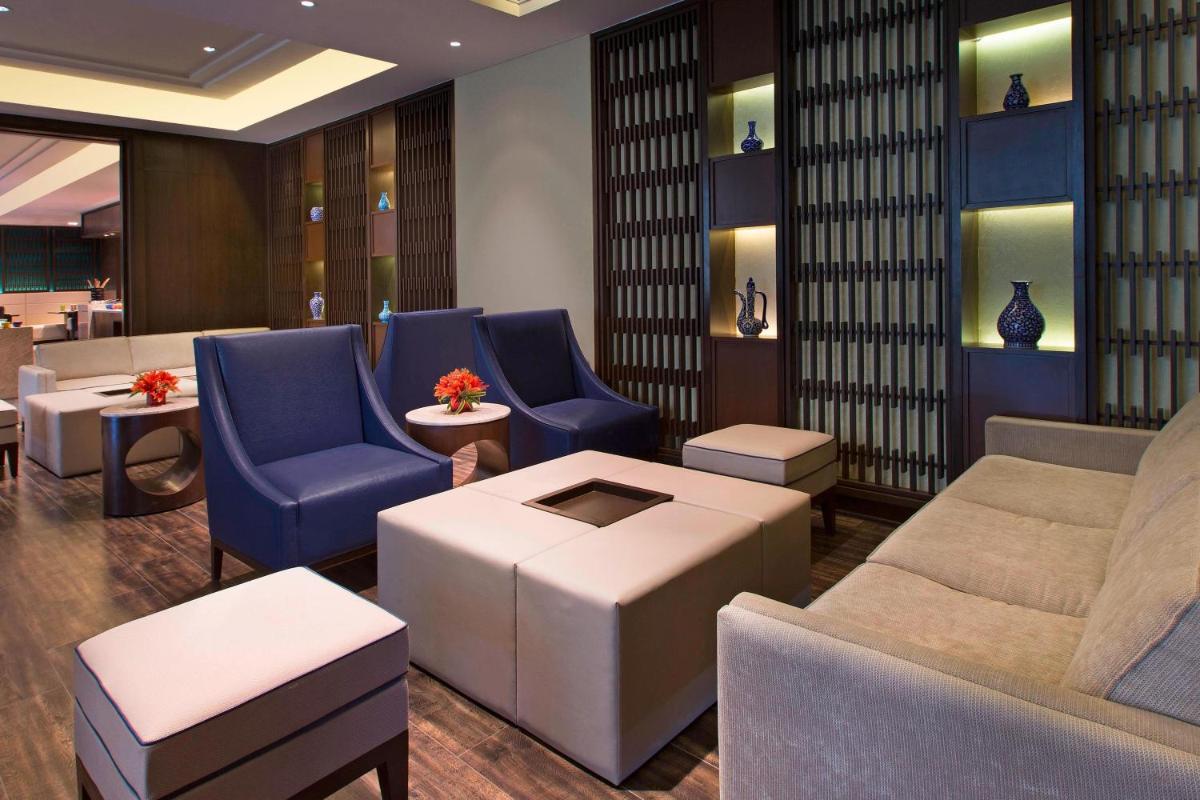 a lobby with blue chairs and a couch and tables at Sheraton Hyderabad Hotel in Hyderabad