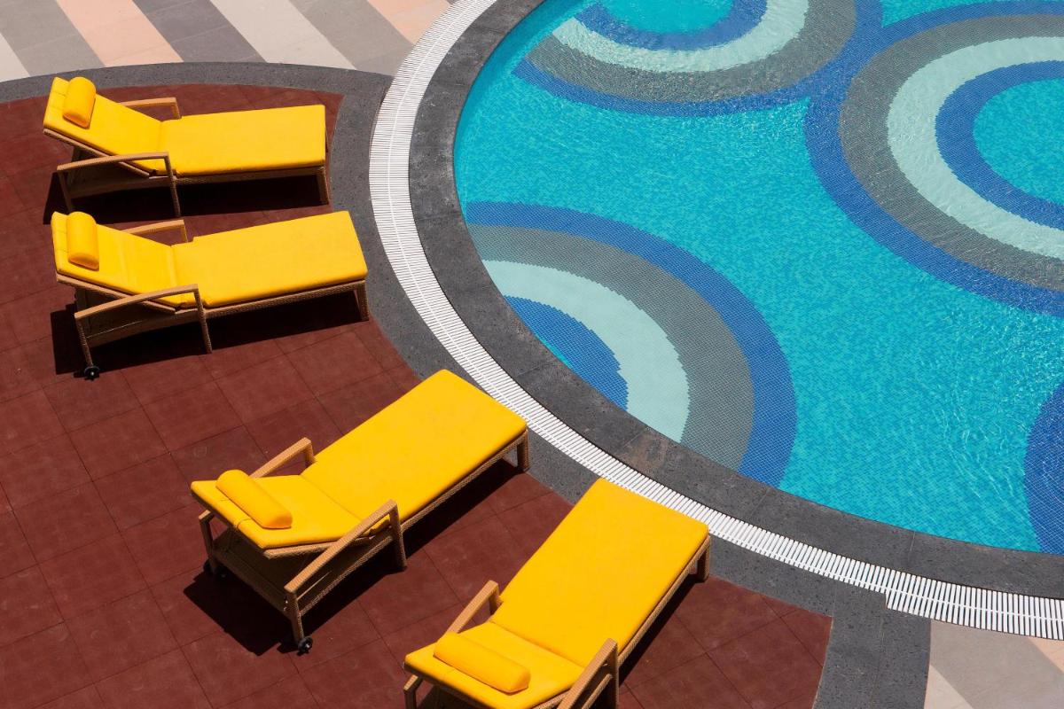an overhead view of chairs next to a swimming pool at Sheraton Hyderabad Hotel in Hyderabad
