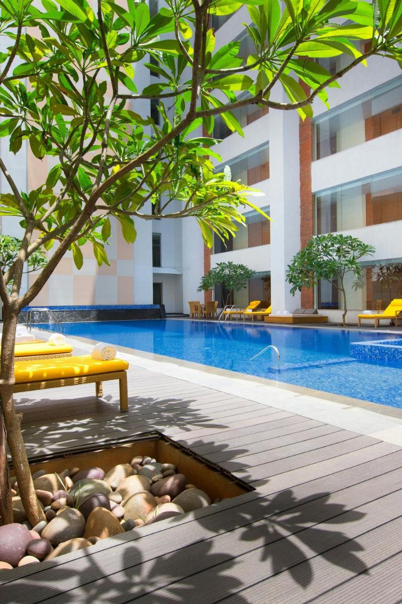 a swimming pool with a tree next to a building at Sheraton Hyderabad Hotel in Hyderabad