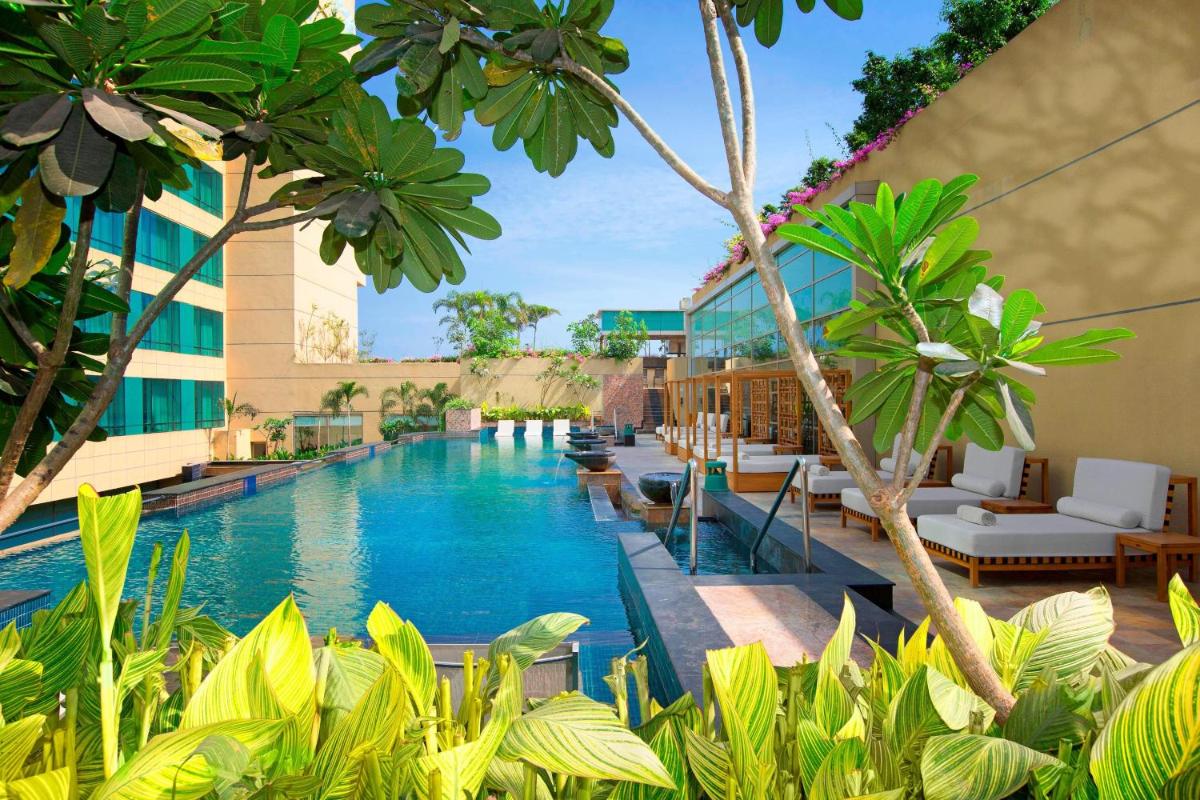 a pool at a hotel with chairs and trees at The Westin Chennai Velachery in Chennai