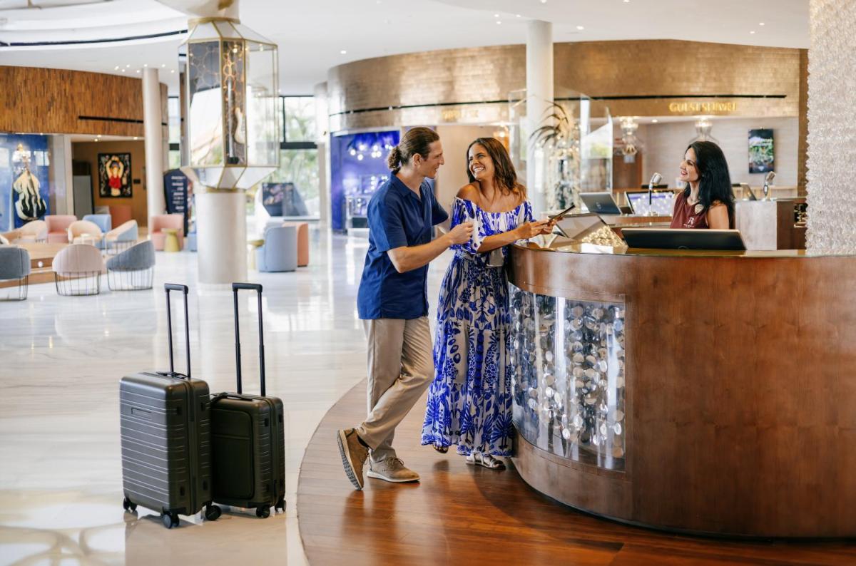 un hombre y una mujer parados en un mostrador en un aeropuerto en Hard Rock Hotel Tenerife, en Adeje 80 fotos más