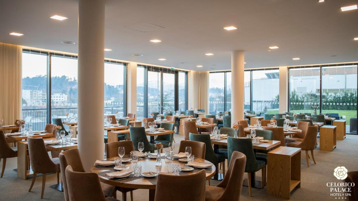um restaurante com mesas e cadeiras e grandes janelas em LAM Hotel Celorico de Basto em Celorico de Basto