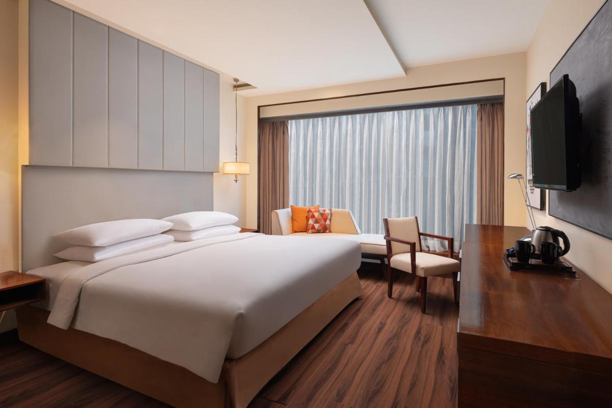 a hotel room with a large bed and a television at Renaissance Ahmedabad Hotel in Ahmedabad