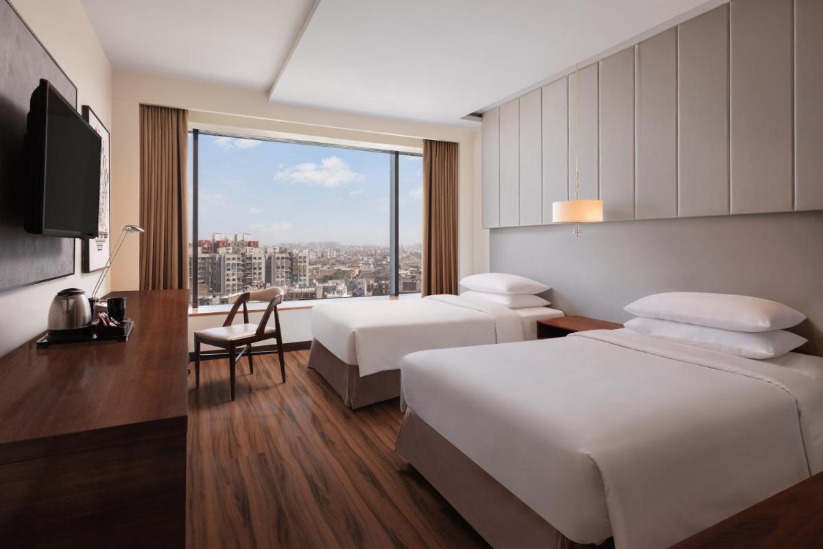 a hotel room with two beds and a window at Renaissance Ahmedabad Hotel in Ahmedabad