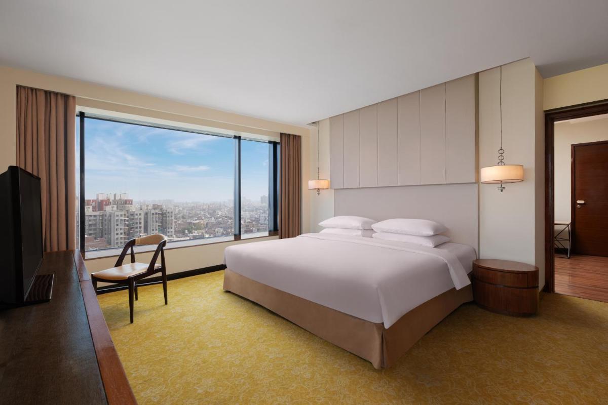 a bedroom with a large bed and a large window at Renaissance Ahmedabad Hotel in Ahmedabad