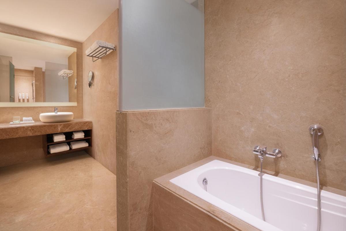 a bathroom with a bath tub and a sink at Renaissance Ahmedabad Hotel in Ahmedabad