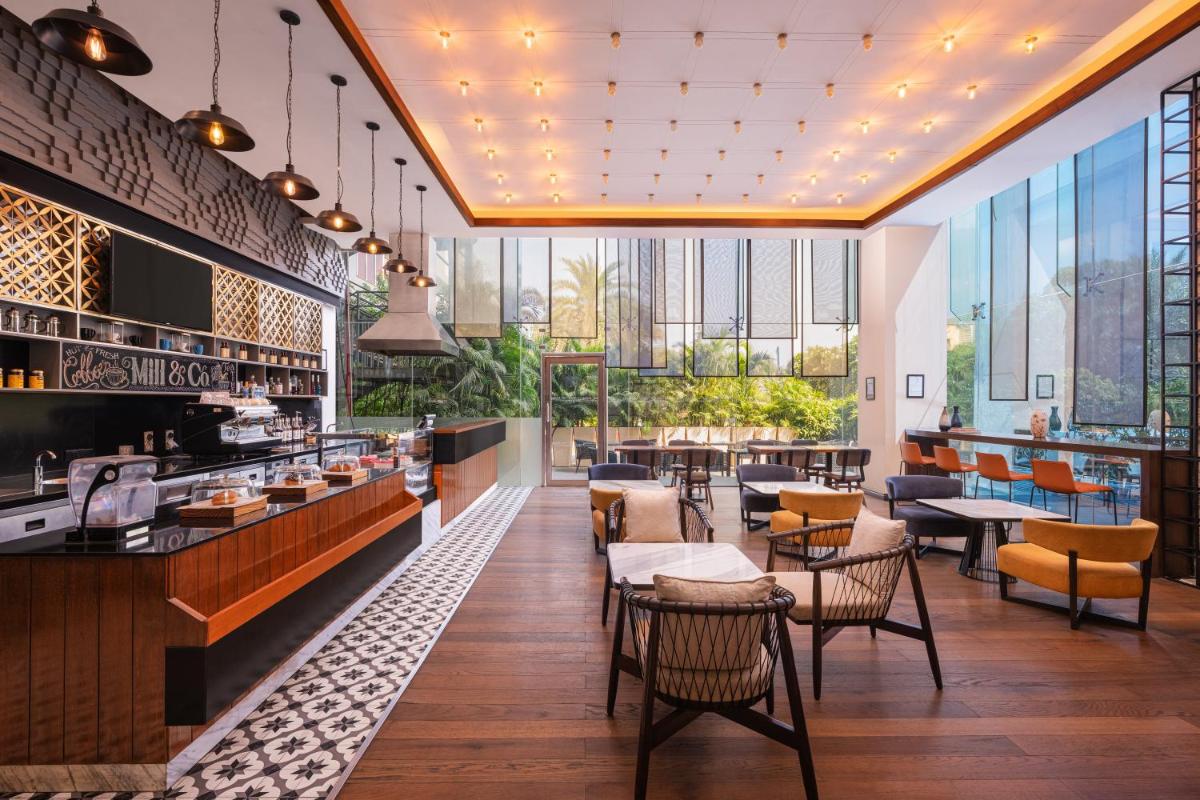 a restaurant with tables and chairs and windows at Renaissance Ahmedabad Hotel in Ahmedabad