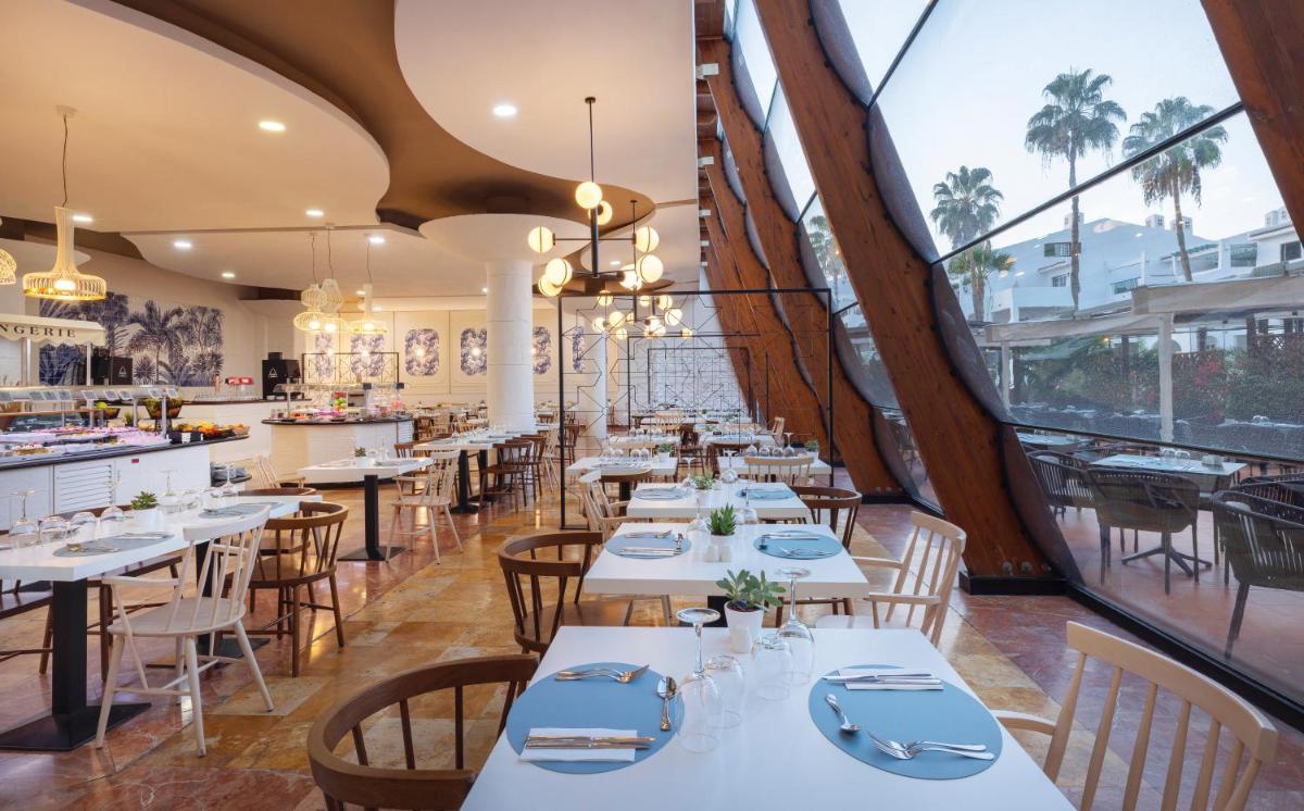 Un restaurante con mesas y sillas blancas y ventanas. en AluaSoul Costa Adeje - Adults Only, en Adeje 103 fotos más