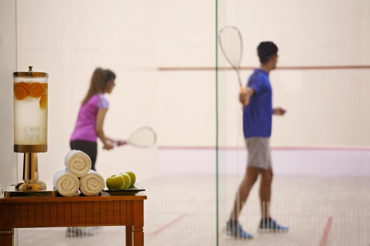 a man and a woman playing tennis in a court at The Westin Pune Koregaon Park in Pune