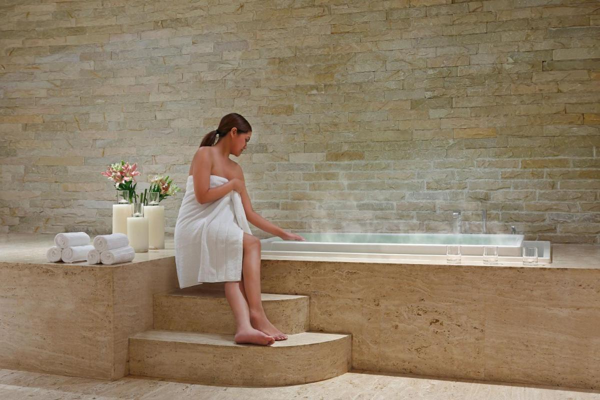 a woman sitting on the edge of a bathtub at The Westin Pune Koregaon Park in Pune