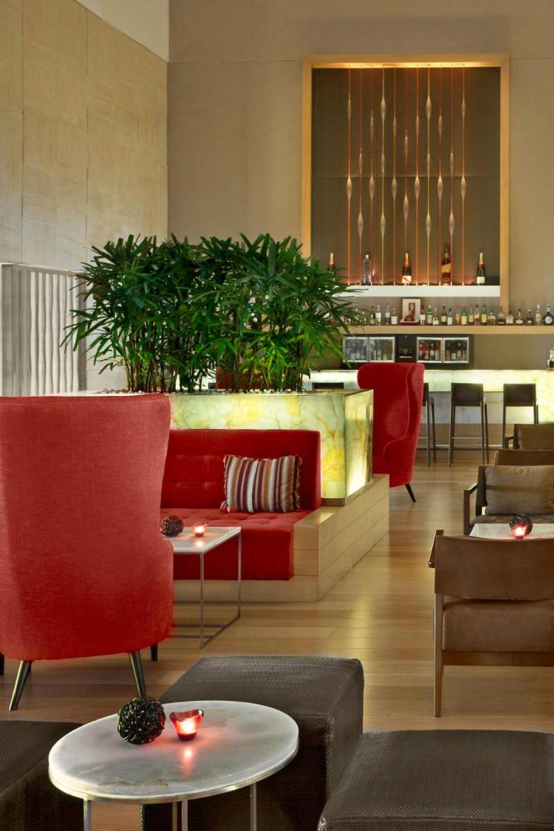a lobby with a red couch and chairs and tables at The Westin Mumbai Garden City in Mumbai