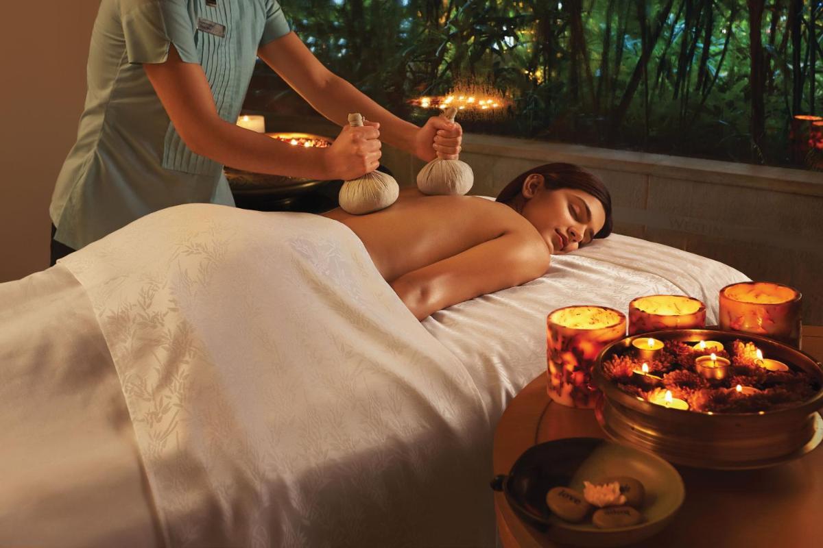 a woman getting a massage in a bed at The Westin Mumbai Garden City in Mumbai