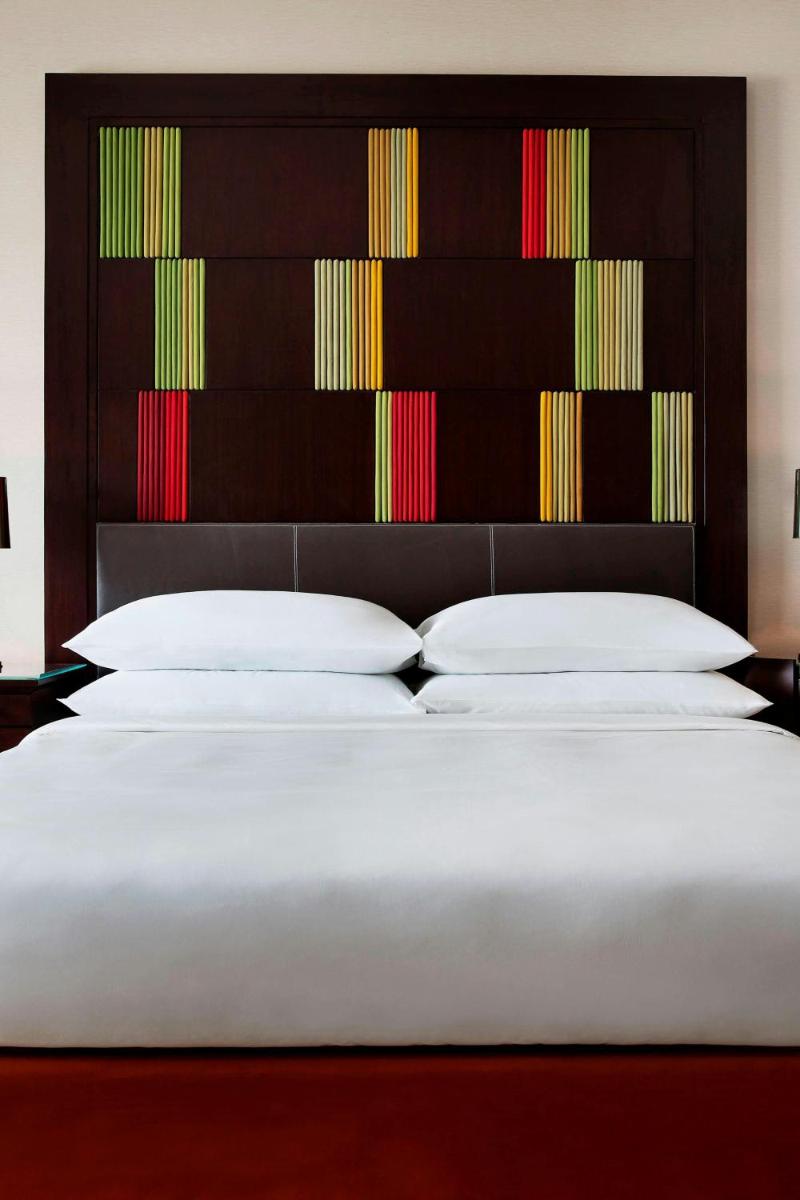 a bedroom with three beds with a large headboard at JW Marriott Hotel Bengaluru in Bengaluru