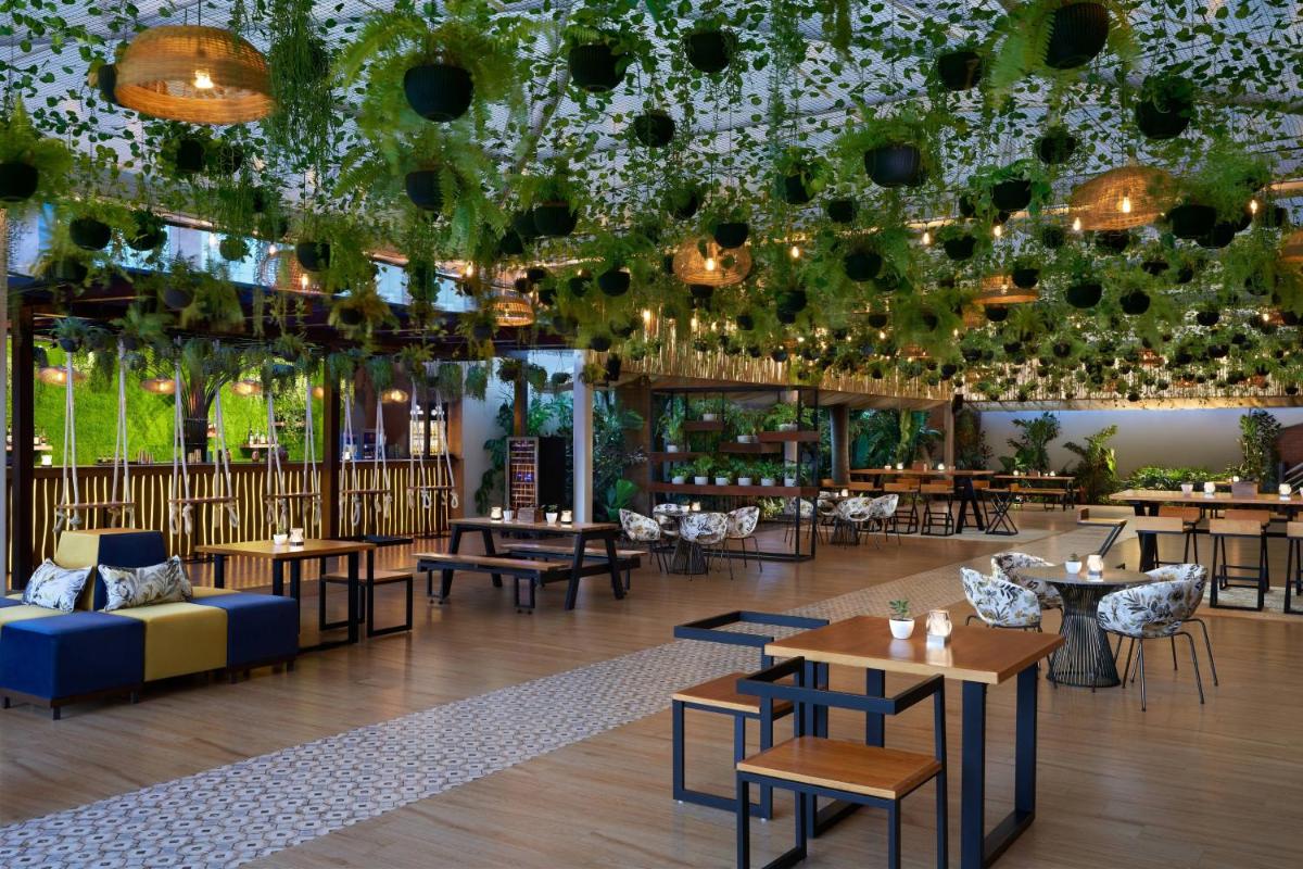 a restaurant with tables and chairs and a ceiling with plants at JW Marriott Hotel Bengaluru in Bengaluru