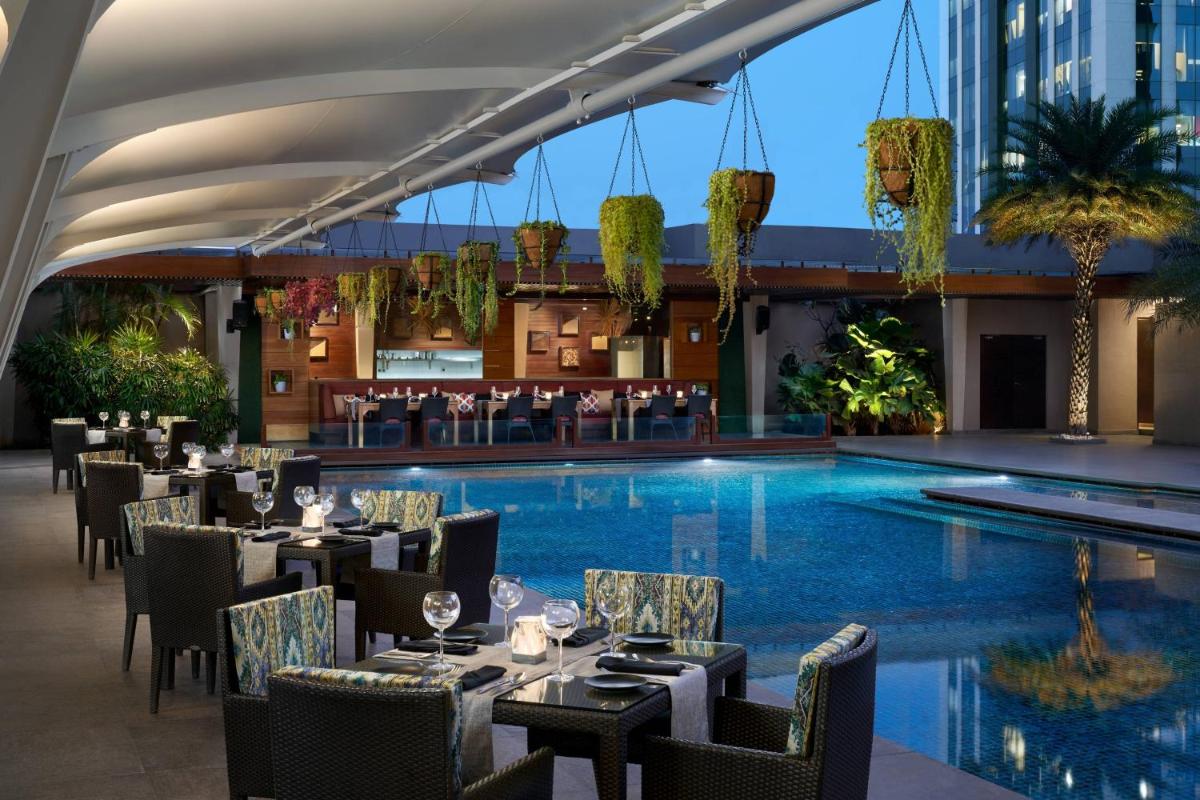 a restaurant with a pool and tables and chairs at JW Marriott Hotel Bengaluru in Bengaluru
