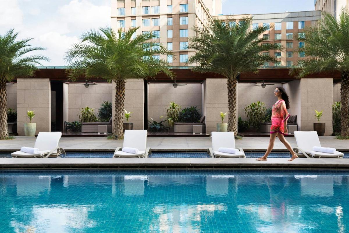a woman walking by a swimming pool at JW Marriott Hotel Bengaluru in Bengaluru