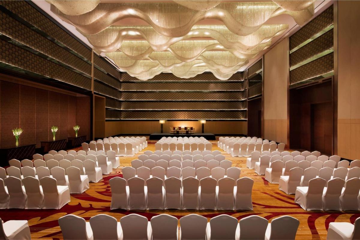an empty banquet hall with white chairs and a ceiling at JW Marriott Hotel Bengaluru in Bengaluru