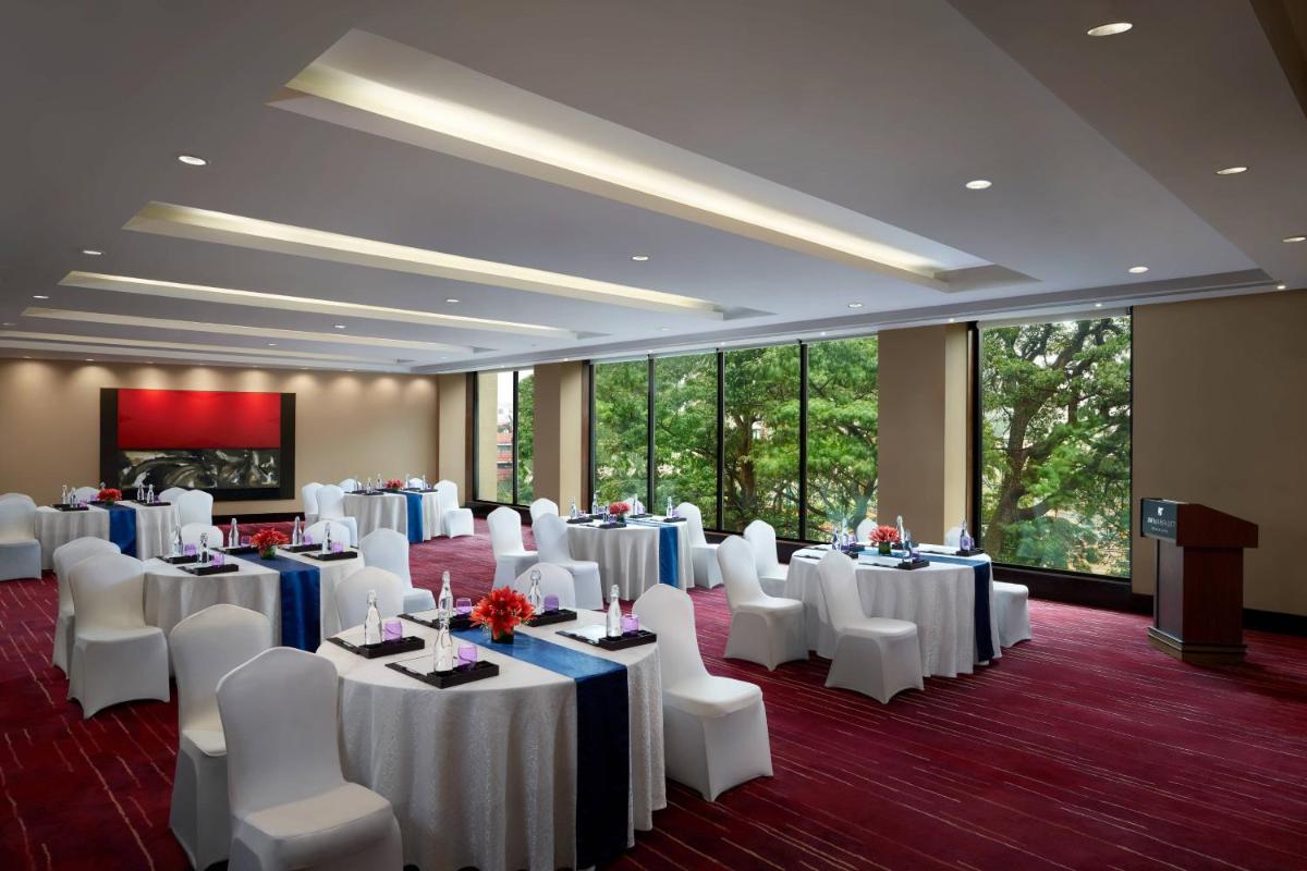 a banquet room with white tables and white chairs at JW Marriott Hotel Bengaluru in Bengaluru