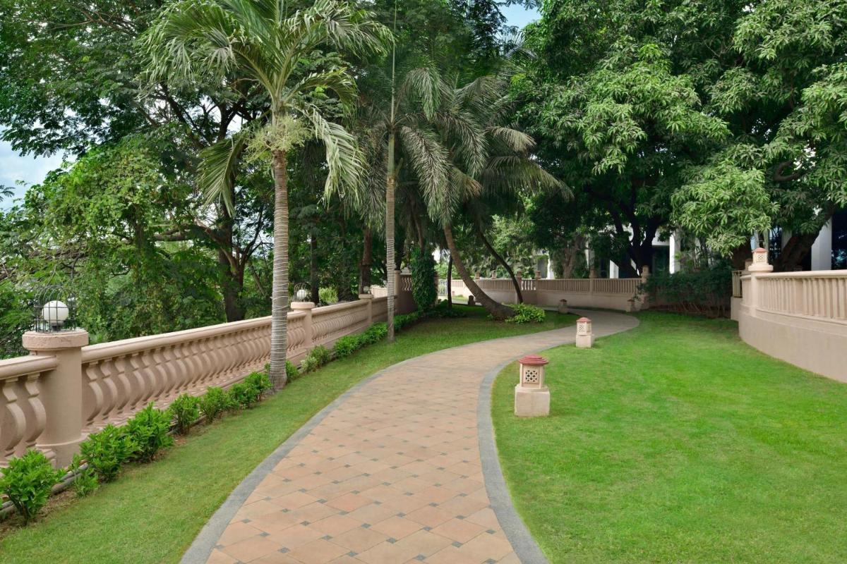 a brick walkway in a park with palm trees at The Westin Mumbai Powai Lake in Mumbai
