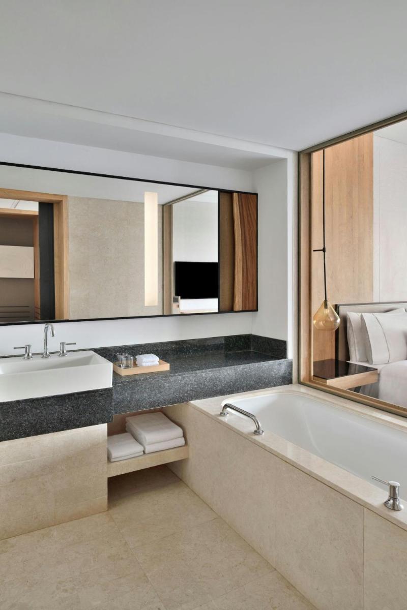 a bathroom with a tub and a sink and a mirror at The Westin Mumbai Powai Lake in Mumbai