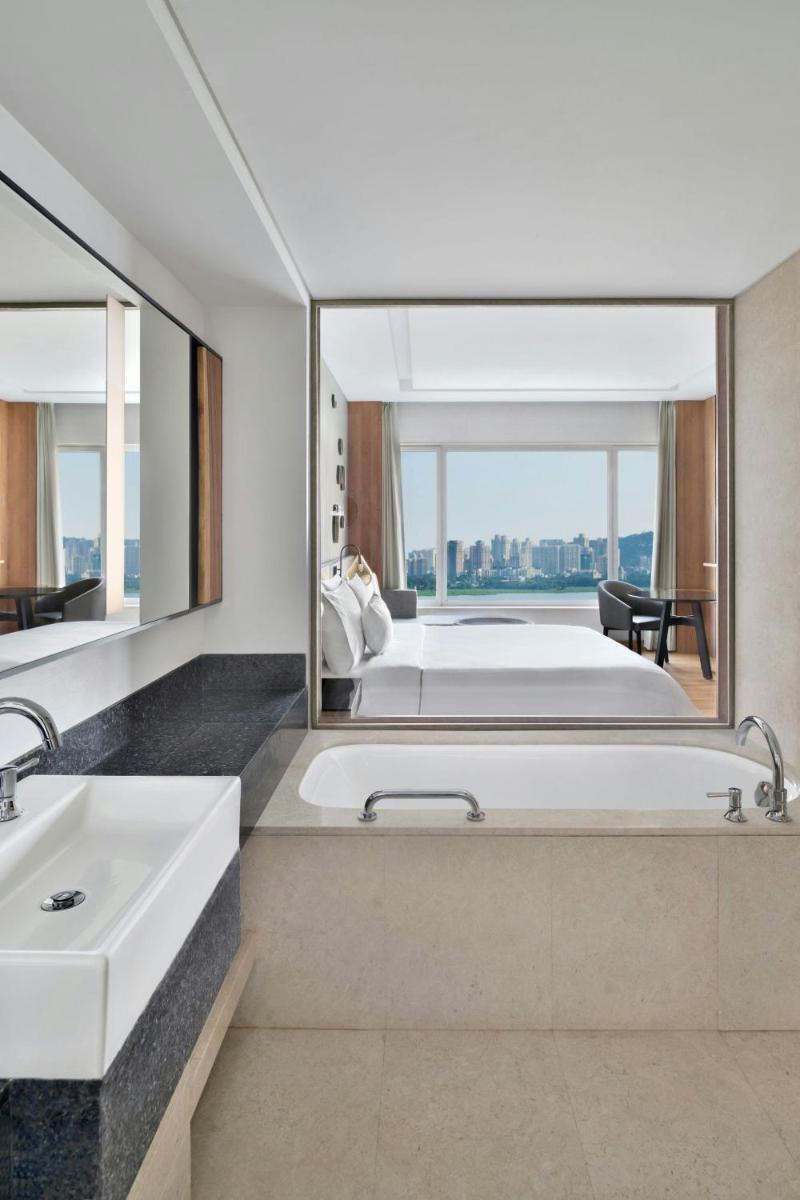 a bathroom with a tub and a bed and a sink at The Westin Mumbai Powai Lake in Mumbai