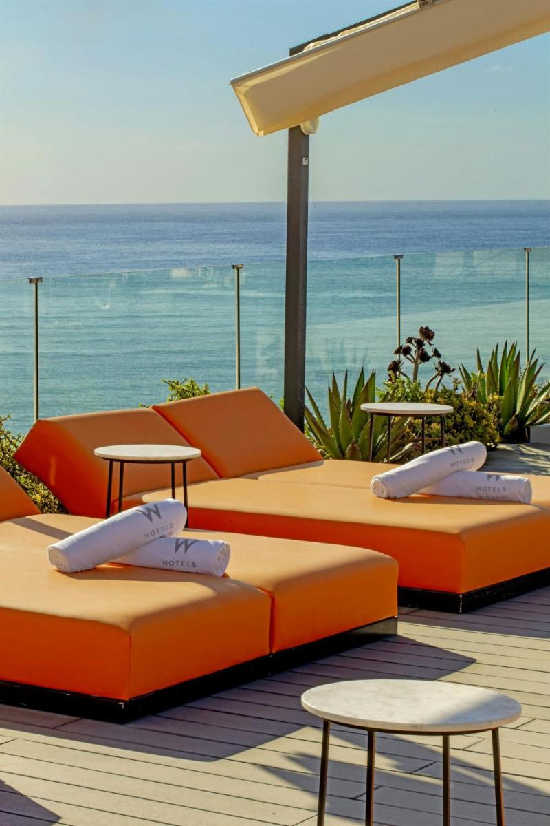 3 camas en una terraza con el océano en el fondo en W Ibiza, en Santa Eulària des Riu