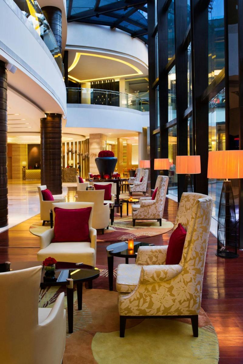 a lobby with couches and chairs and tables at Bengaluru Marriott Hotel Whitefield in Bengaluru