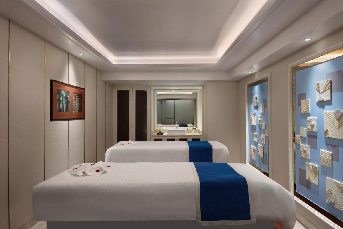 two beds in a room with a bathroom at Sheraton Grand Pune Bund Garden Hotel in Pune