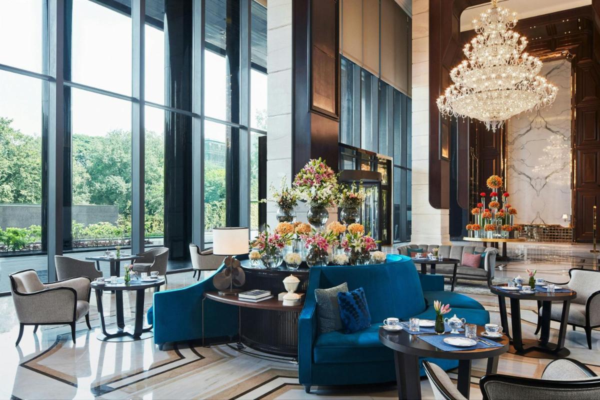 a hotel lobby with tables and chairs and a chandelier at The Ritz-Carlton, Pune in Pune
