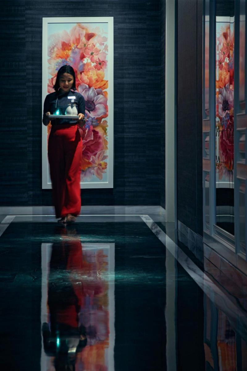 a woman walking in a room with a reflection in the water at The Ritz-Carlton, Pune in Pune