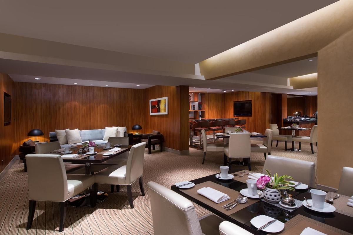 a restaurant with tables and chairs and a piano at Sheraton Grand Bangalore Hotel at Brigade Gateway in Bengaluru