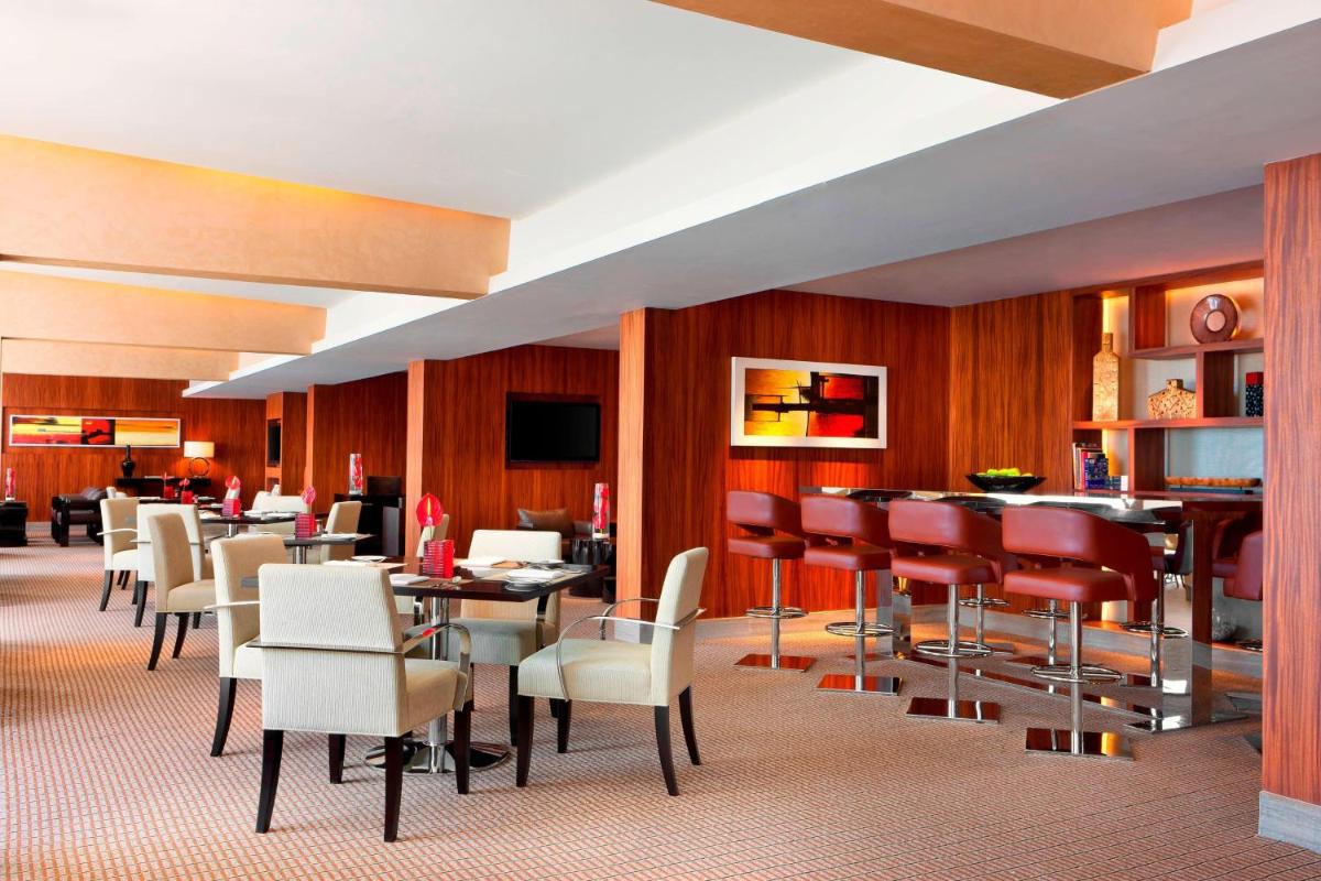 a restaurant with chairs and tables and a bar at Sheraton Grand Bangalore Hotel at Brigade Gateway in Bengaluru