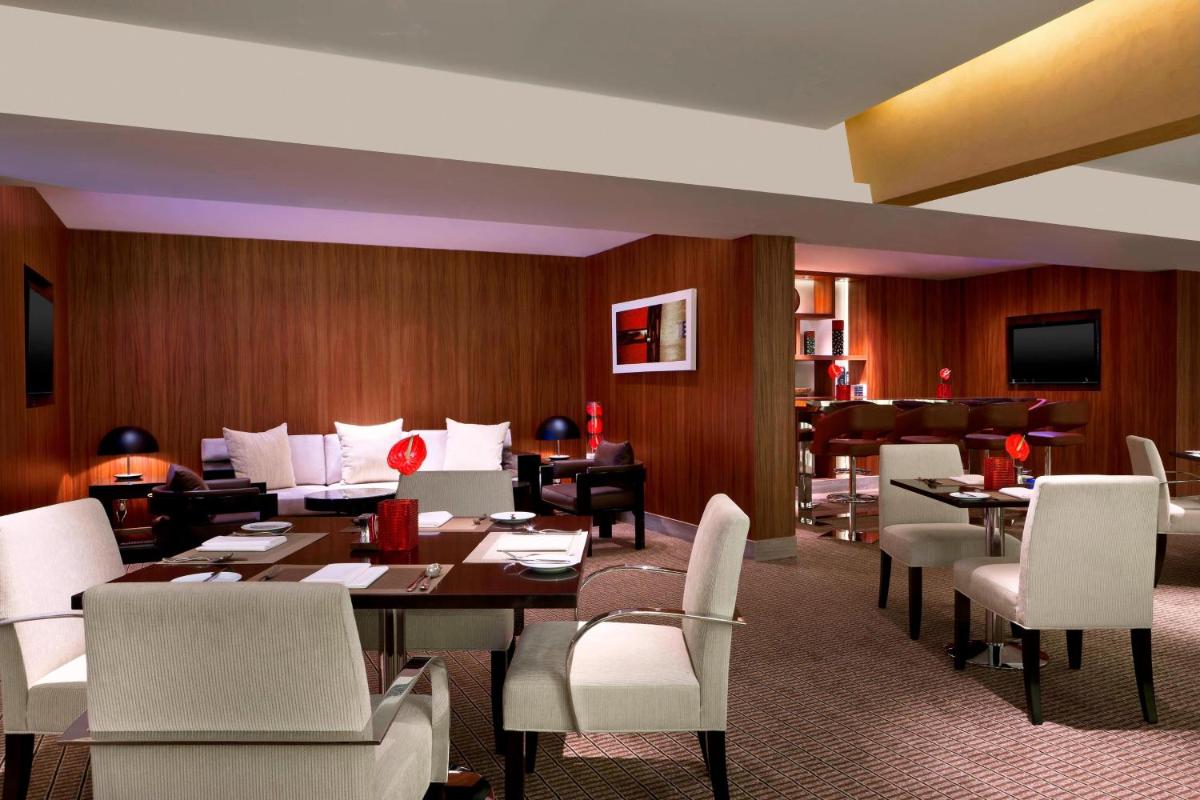 a dining room with a table and white chairs at Sheraton Grand Bangalore Hotel at Brigade Gateway in Bengaluru