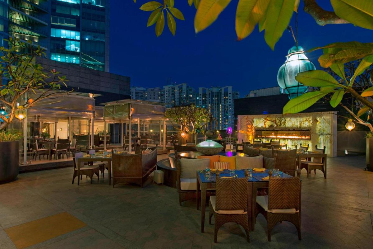 a restaurant with tables and chairs on a rooftop at night at Sheraton Grand Bangalore Hotel at Brigade Gateway in Bengaluru