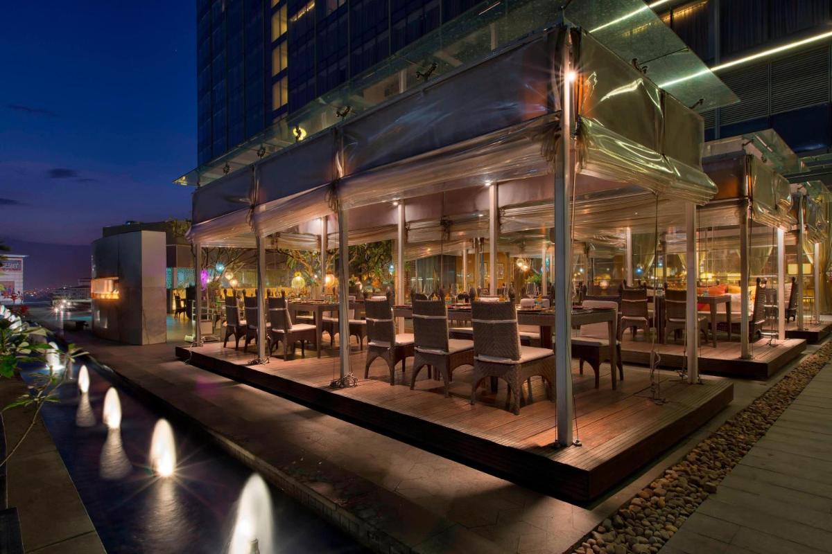 a restaurant with tables and chairs in front of a building at Sheraton Grand Bangalore Hotel at Brigade Gateway in Bengaluru