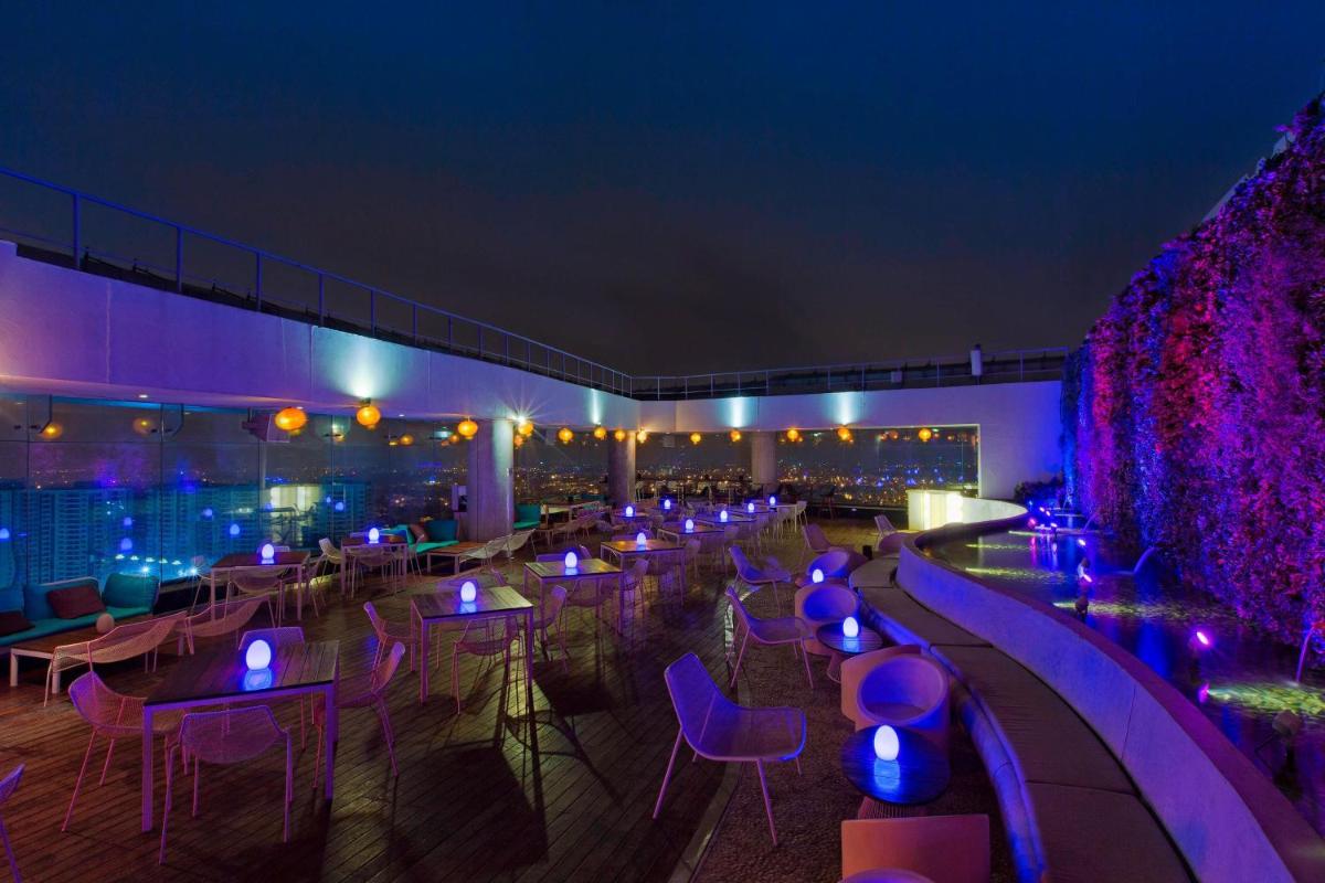 a restaurant with purple lighting and tables and chairs at Sheraton Grand Bangalore Hotel at Brigade Gateway in Bengaluru