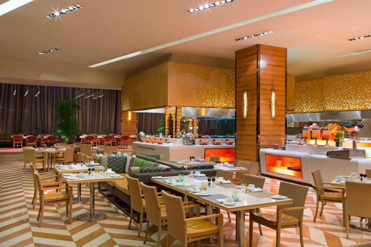 a restaurant with tables and chairs and a kitchen at Sheraton Grand Bangalore Hotel at Brigade Gateway in Bengaluru
