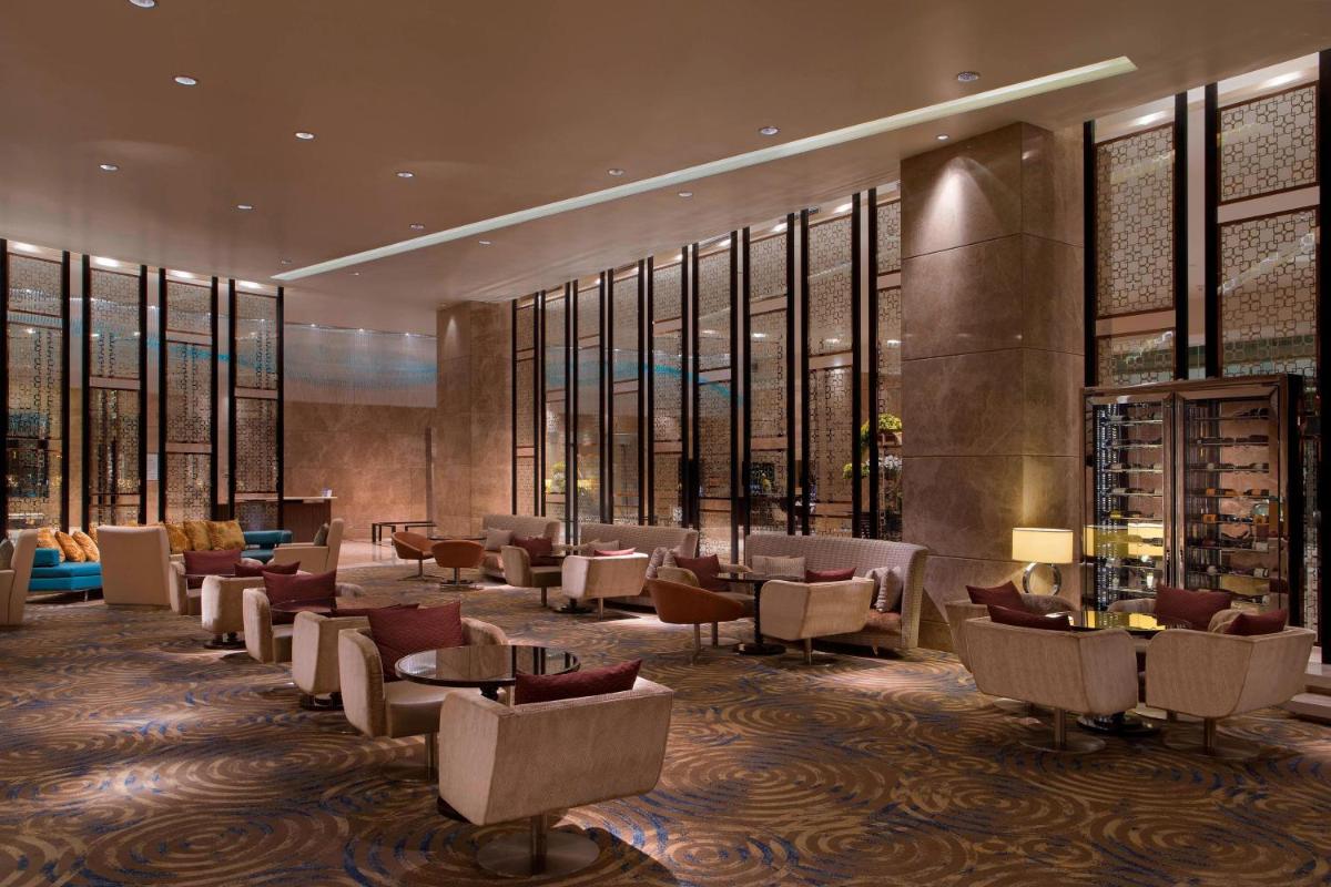 a hotel lobby with chairs and tables and windows at Sheraton Grand Bangalore Hotel at Brigade Gateway in Bengaluru