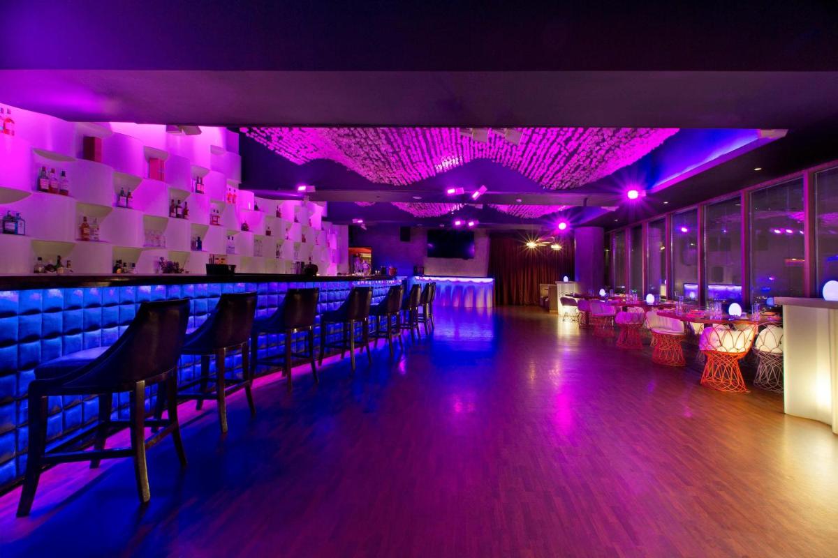 a bar with purple lights and chairs in a room at Sheraton Grand Bangalore Hotel at Brigade Gateway in Bengaluru