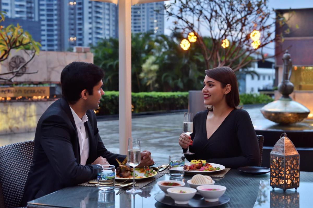a man and woman sitting at a table with wine glasses at Sheraton Grand Bangalore Hotel at Brigade Gateway in Bengaluru