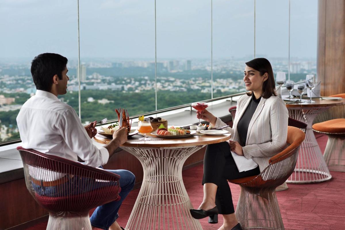 a man and woman sitting at a table in a restaurant at Sheraton Grand Bangalore Hotel at Brigade Gateway in Bengaluru