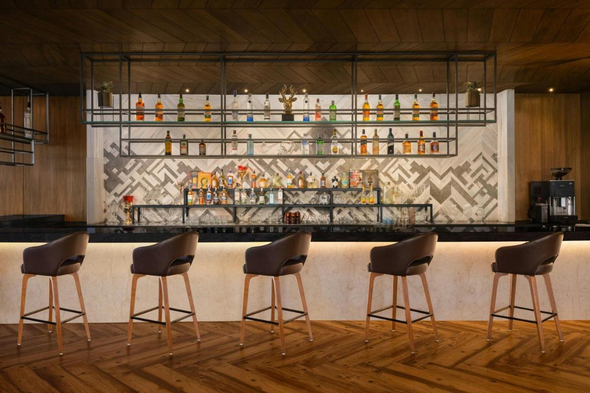 a bar with four chairs in front of a counter at Courtyard by Marriott Amritsar in Amritsar