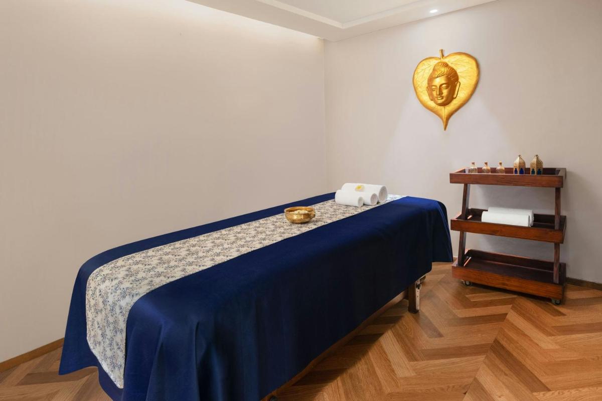 a bedroom with a bed with a blue blanket and a table at Courtyard by Marriott Amritsar in Amritsar