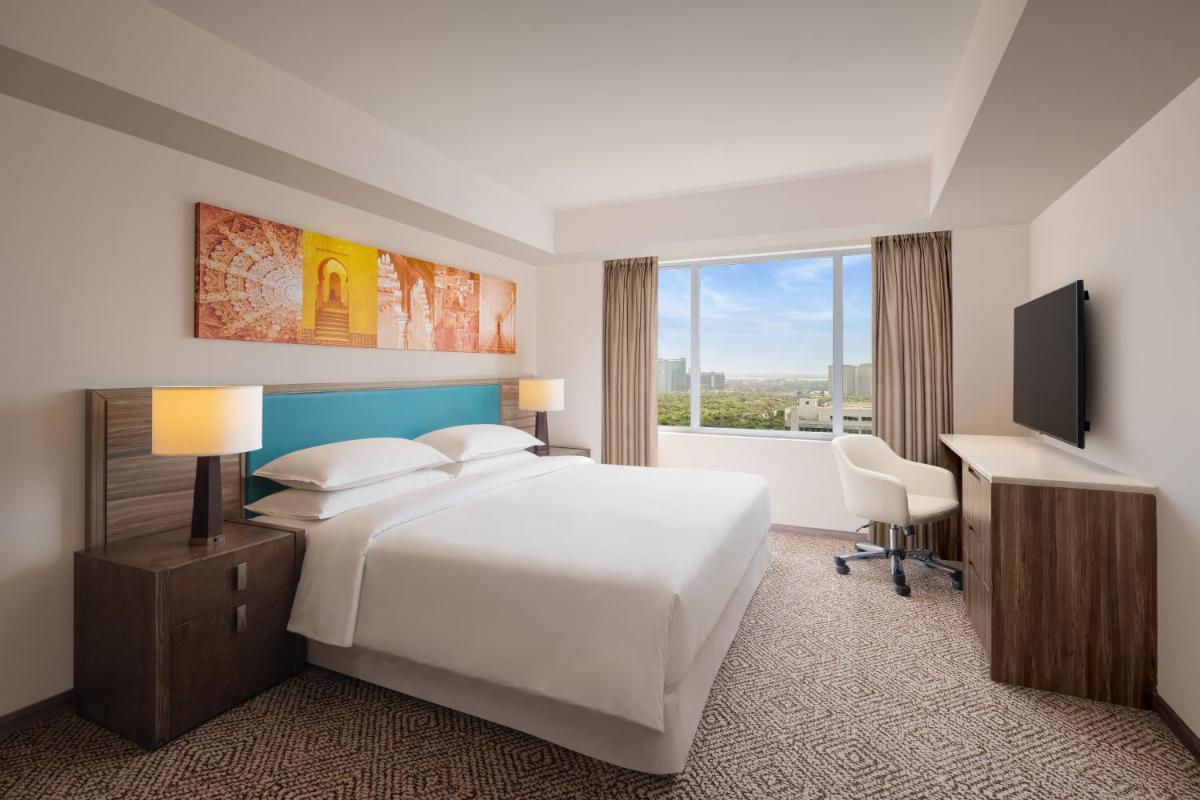 a hotel room with a bed and a desk and a television at Sheraton Hyderabad Hotel in Hyderabad