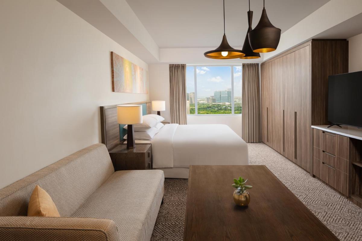 a hotel room with a bed and a couch and a tv at Sheraton Hyderabad Hotel in Hyderabad