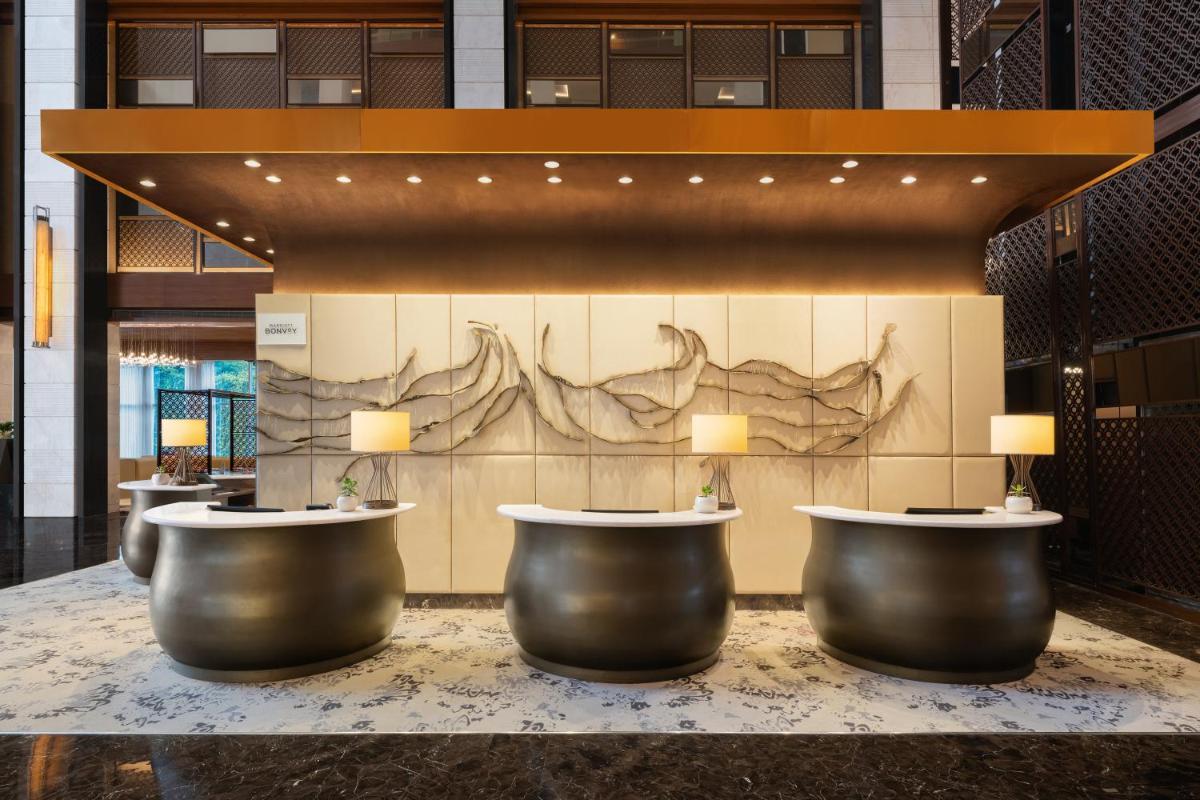 a lobby with a row ofools in front of a wall at Sheraton Hyderabad Hotel in Hyderabad