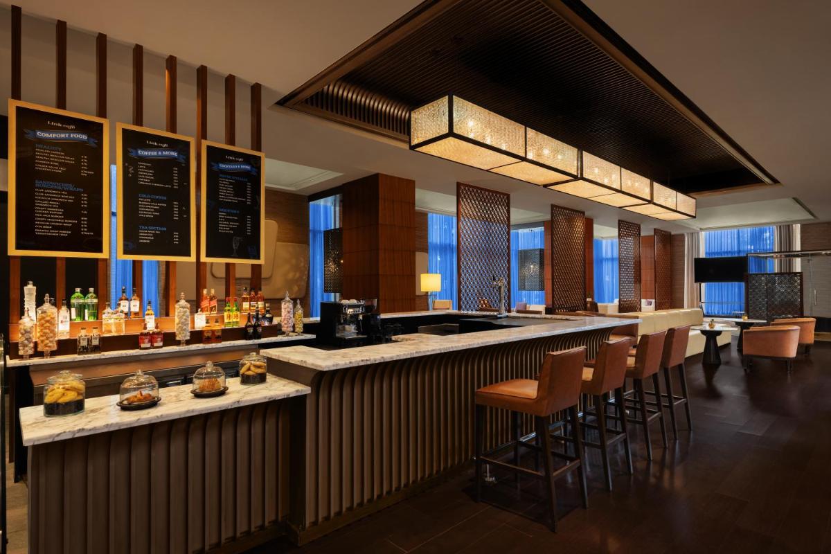 a bar with brown stools and a counter with drinks at Sheraton Hyderabad Hotel in Hyderabad