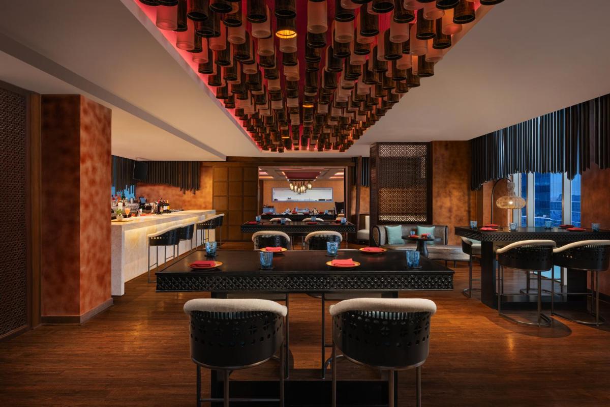 a dining room with a table and chairs at Sheraton Hyderabad Hotel in Hyderabad